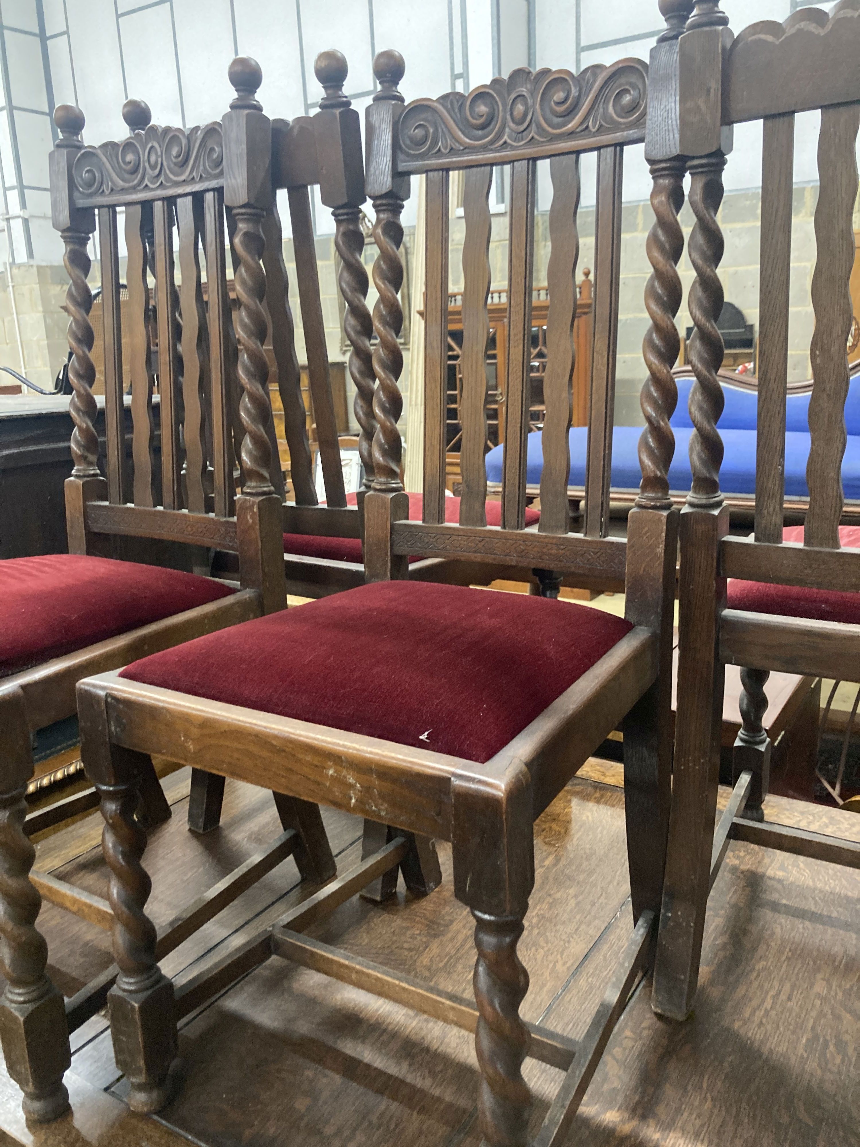 A set of six 1920s oak Carolean style dining chairs (two with arms) and an oak draw leaf dining table, width 137cm, depth 106cm, heigh